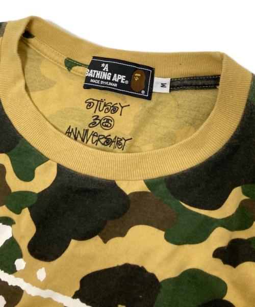 A BATHING APE（アベイシングエイプ）A BATHING APE (アベイシングエイプ) stussy (ステューシー) 30周年記念 1stカモ 猿迷彩 ワールドツアー Tシャツ ベージュ×グリーン サイズ:Mの古着・服飾アイテム