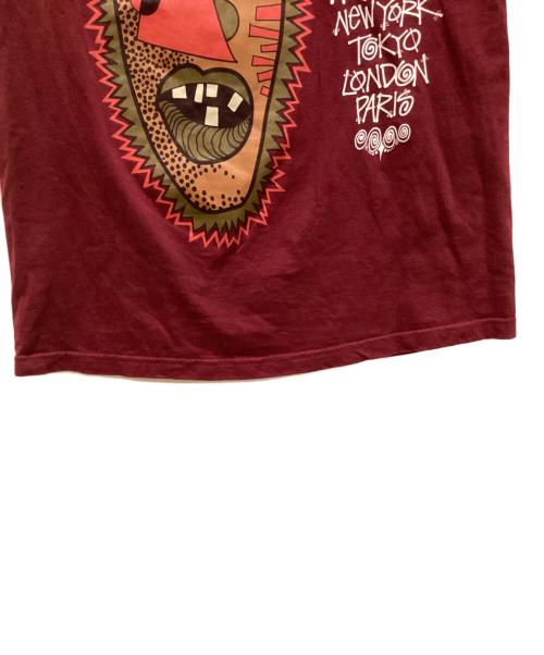 stussy（ステューシー）stussy (ステューシー) トライバルマスクプリントTシャツ パープル サイズ:Sの古着・服飾アイテム