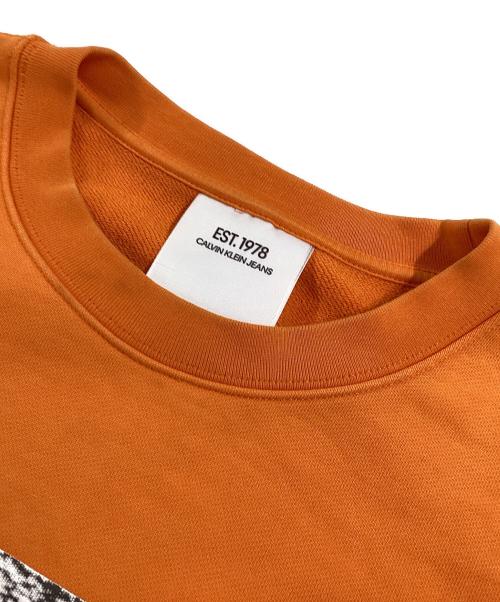 Calvin Klein Jeans（カルバンクラインジーンズ）Calvin Klein Jeans (カルバンクラインジーンズ) プリントスウェット オレンジ サイズ:Lの古着・服飾アイテム
