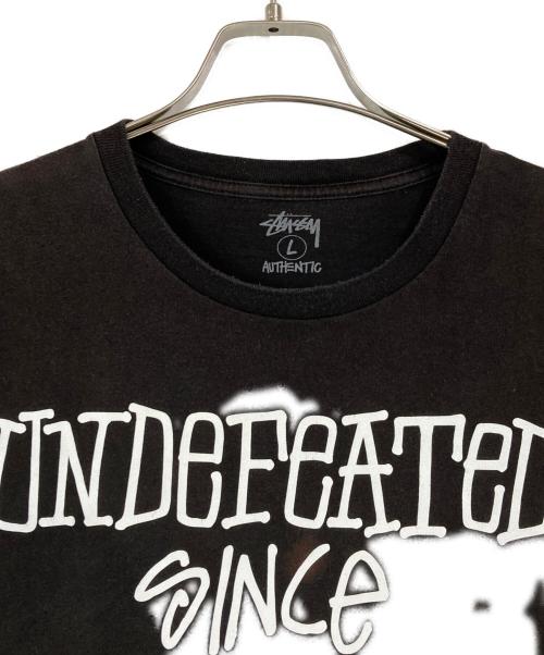 stussy（ステューシー）stussy (ステューシー) UNDEFEATED (アンディフィーテッド) プリントTシャツ ブラック サイズ:Lの古着・服飾アイテム