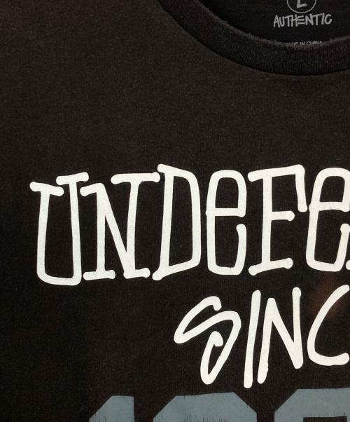 stussy（ステューシー）stussy (ステューシー) UNDEFEATED (アンディフィーテッド) プリントTシャツ ブラック サイズ:Lの古着・服飾アイテム