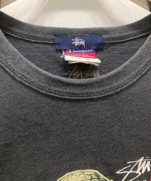 stussy（ステューシー）stussy (ステューシー) Champion (チャンピオン) 別注プリントTシャツ ブラック サイズ:Mの古着・服飾アイテム